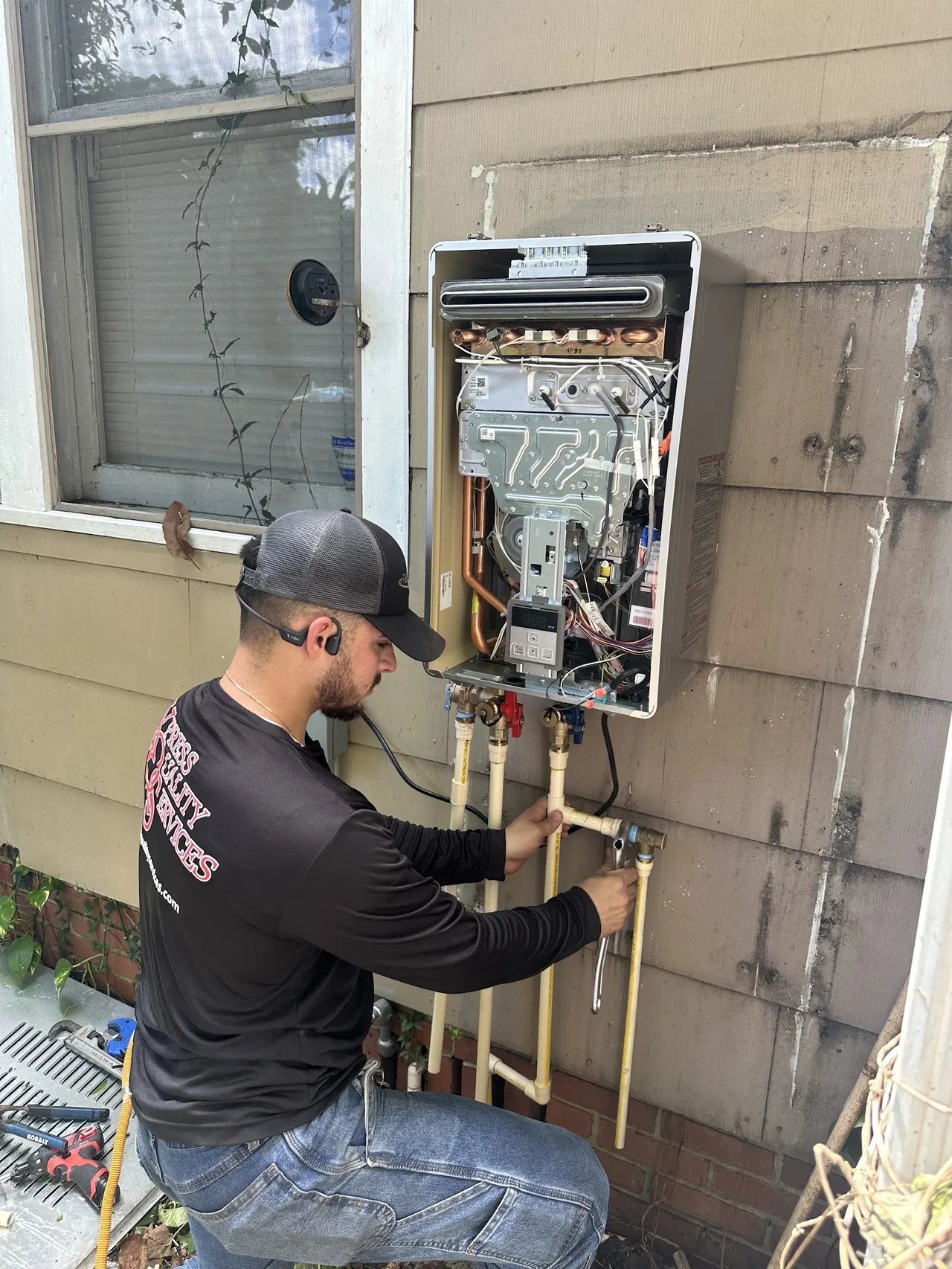 XQS technician installing a tankless water heater, photo from XQS Google Business Profile