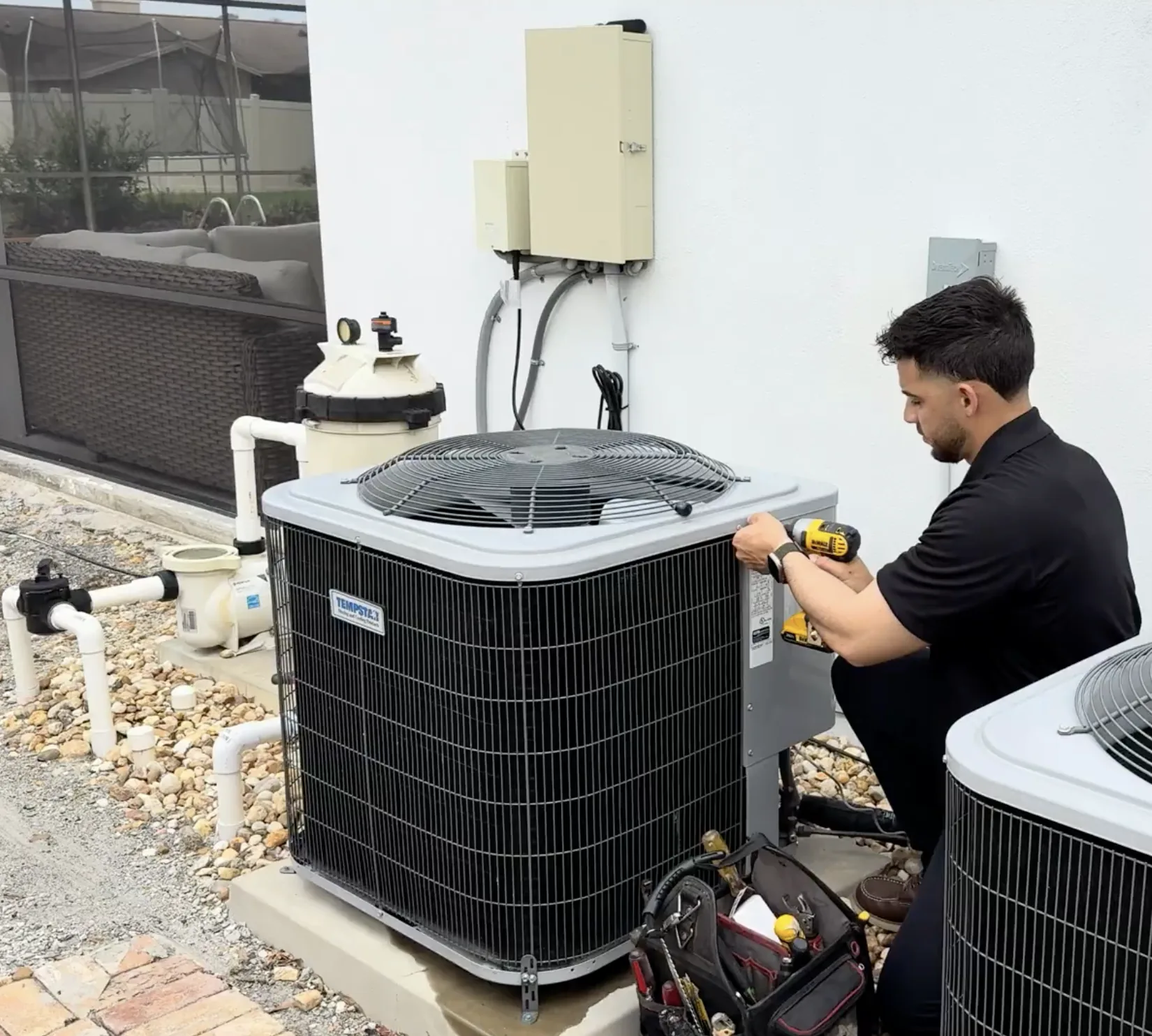 Technician using a tool beside an outdoor air conditioning unit, published by XQS